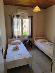 two beds in a small room with a window at George apartment in Artemida