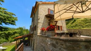 ein Steinhaus mit einem Tisch und einem Sonnenschirm in der Unterkunft Poet's Rest in Pieve Santo Stefano