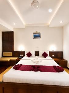 a bedroom with a large white bed with red pillows at Hotel Xavier's Avenue in Kadavoor