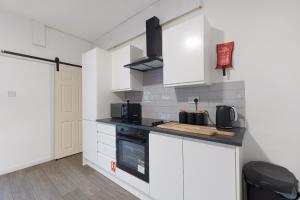 a kitchen with white cabinets and a stove at Cosy 2BR Apartment Sleeps 4 by Stay With Us in Hawthorn