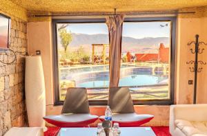 a living room with a view of a swimming pool through a window at Hotel Bin El Ouidane in Bine el Ouidane