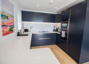 a kitchen with black cabinets and white counters at Marine View Apartment by Air Premier in Seaford