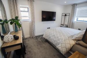a bedroom with a bed and a tv on the wall at Marine View Apartment by Air Premier in Seaford