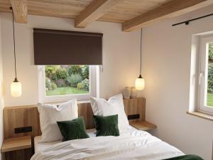 a bedroom with a bed with white sheets and green pillows at Heidehaus in Lilienthal