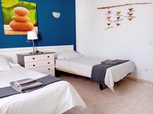 a bedroom with two beds and a painting of a stack of eggs at Villas Reina in Costa Teguise +108 photos
