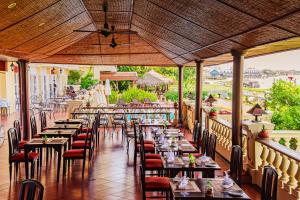 a restaurant with tables and chairs and a balcony at Victoria Chau Doc Hotel in Chau Doc