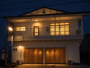 a white house with a balcony and two garage doors at Takamori Guest House in Takamori