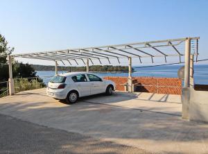 a white car is parked under a metal canopy at Apartments Bacic in Prizba