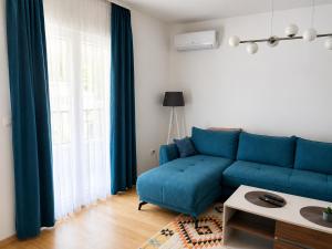 a living room with a blue couch in front of a window at Apartpan Lekic in Bar