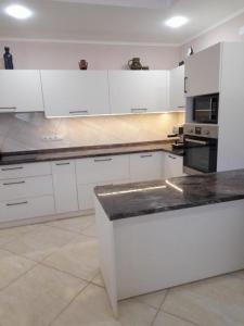 a kitchen with white cabinets and a black counter top at Argo rooms in Berehove