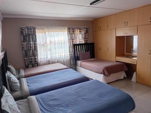 a bedroom with two beds and a kitchen with a window at Radies Bed and Breakfast in Cofimvaba +8 photos