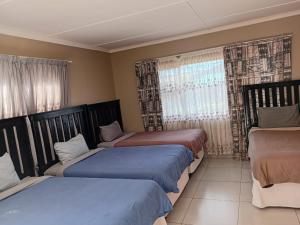 a bedroom with three beds and a window at Radies Bed and Breakfast in Cofimvaba
