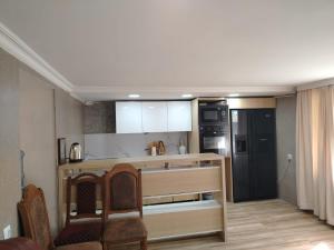 a kitchen with a counter with chairs and a refrigerator at Ghulelebi - ღულელები in Ghulelebi