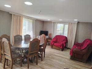 a dining room with a table and chairs and a couch at Ghulelebi - ღულელები in Ghulelebi