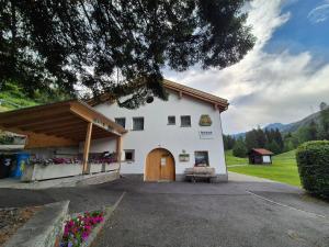 a white building with a brown door and flowers at FeWo Aquileia Scuol, Gratisparken, Terrasse, Wifi, flexible Zimmerwahl, Familien in Scuol