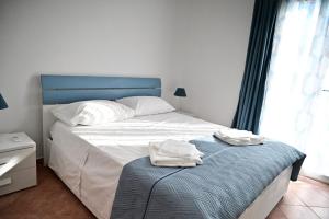 a bedroom with a bed with a blue headboard and two towels at Casa Marina in Balestrate