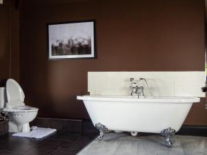 a bathroom with a white tub and a toilet at Cheshire Yeoman - Station Hotel in Hooton Station +17 photos