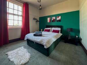 a green bedroom with a bed and a green wall at Cheshire Yeoman - Station Hotel in Hooton Station
