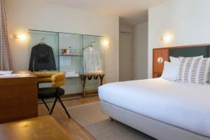 a bedroom with a bed and a desk and a dressing room at Hôtel La Pérouse in Nantes