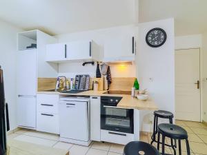 a kitchen with white cabinets and a clock on the wall at La Beaujoire in Nantes