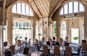 a dining room with tables and chairs and windows at Audleys Wood Hotel, Basingstoke in Basingstoke +26 photos