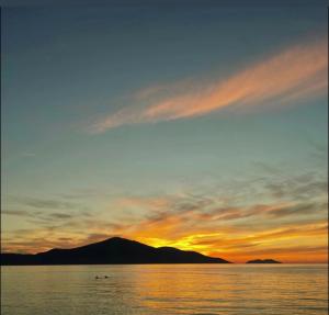 a sunset over a body of water with a mountain at BNB Alehandro in Radhimë
