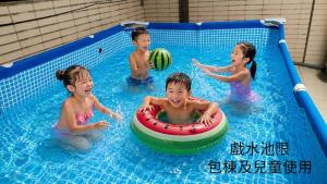 three children playing with a ball in a swimming pool at 宜蘭頭城多一點民宿 in Toucheng