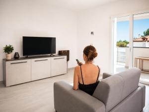 a woman sitting on a chair in a living room with a television at Pierre Palace in Isola Sacra