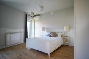 a white bedroom with a white bed and a window at La Corte 27 - A in Sesto Calende