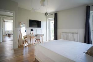 a bedroom with a white bed and a desk with a mirror at La Corte 27 - A in Sesto Calende