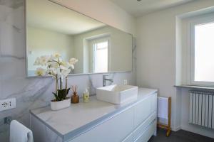 a white bathroom with a sink and a mirror at La Corte 27 - A in Sesto Calende +10 photos