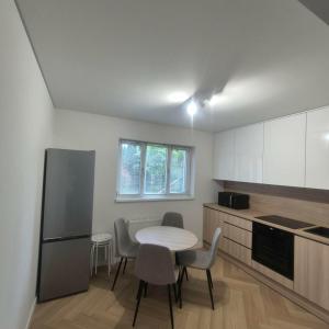 a kitchen with a table and chairs and a refrigerator at Willa Na Deptaku in Pobierowo