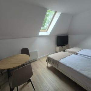 a bedroom with a bed and a table and a window at Willa Na Deptaku in Pobierowo