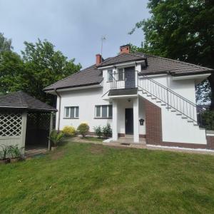 a white house with a balcony and a yard at Willa Na Deptaku in Pobierowo
