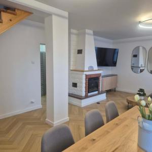 a living room with a fireplace and a table and chairs at Willa Na Deptaku in Pobierowo