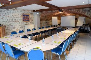 a conference room with tables and chairs and a whiteboard at Hostellerie du Forez in Saint-Galmier