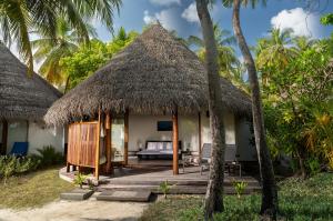 a resort with a bed and a thatch roof at Niva Kuramathi Maldives in Rasdhoo