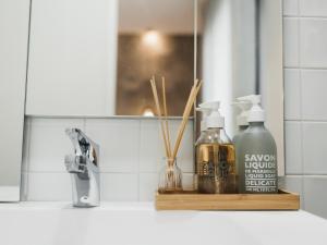 a bathroom counter with two bottles of soap and a mirror at &Tales Suites - Óbidos in Óbidos