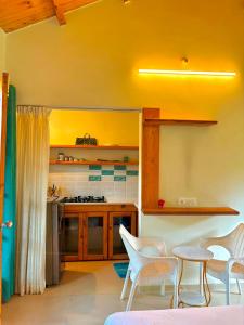a kitchen with white chairs and a table and a counter at Harmals Studios & Apartments in Arambol
