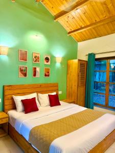 a bedroom with a large bed with green walls at Harmals Studios & Apartments in Arambol