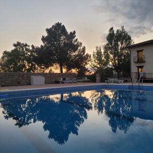 a swimming pool with a house and trees in the background at LA CANTERICA in Fuentes de Rubielos