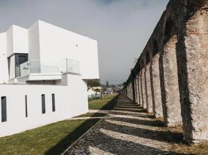 an old brick wall next to a white building at &Tales Suites - Óbidos in Óbidos