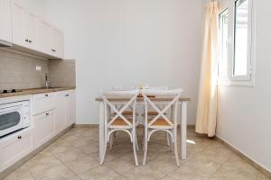 a white kitchen with a table and two stools at Anemologio 303 Tinos in Agios Ioannis