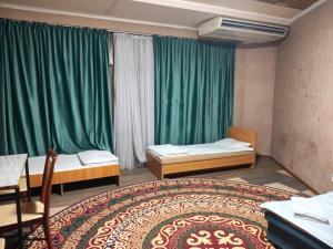 two beds in a room with green curtains at SALEM hotel in Türkistan