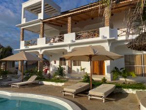 a large white building with a swimming pool and umbrellas at Ocean view in Watamu