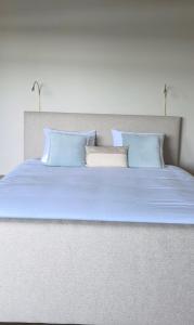 a large white bed with blue pillows on it at B&B La Rivé in Maastricht