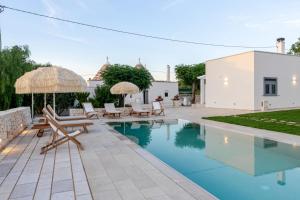 a pool with chairs and umbrellas next to a house at Pavì Trulli e Suites in Locorotondo