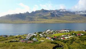 eine kleine Stadt vor einem Berg mit einem Gewässer in der Unterkunft Stöð-INN in Stöðvarfjörður