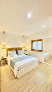 a white bedroom with a large bed and a window at Refúgio do Espigueiro in Amarante