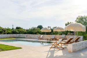 a patio with chairs and umbrellas next to a pool at Pavì Trulli e Suites in Locorotondo